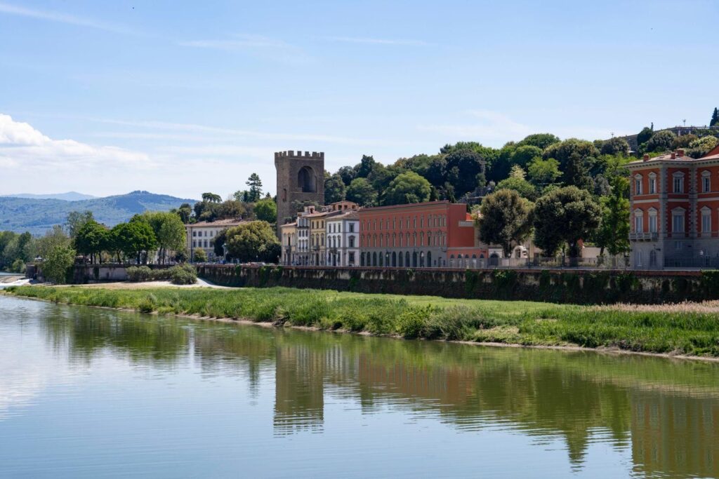 L'Arno a San Niccolò con le case riflesse nell'acqua; sullo sfondo la torre e la facciata rossa di Palazzo San Giorgio
