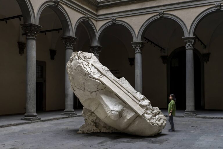 Silent Studio di Mark Manders: un grande frammento chiaro e crepato nel cortile di Palazzo Strozzi, accanto a una visitatrice