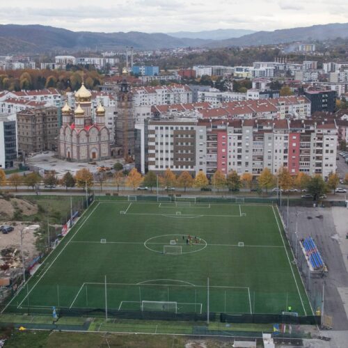 Il campo d'allenamento dell'FK Borac visto dall'alto, fra palazzi, un cantiere e una chiesa dalle cupole dorate