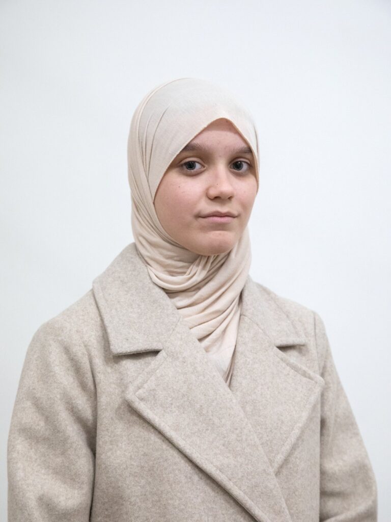 Ritratto di Ajila Masić, studentessa della madrasa islamica di Banja Luka, con il velo e un cappotto chiaro su fondo bianco