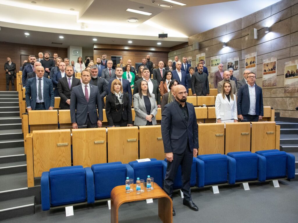 Deputati in piedi fra le poltrone blu dell'aula della Camera dei rappresentanti della Federazione di Bosnia ed Erzegovina