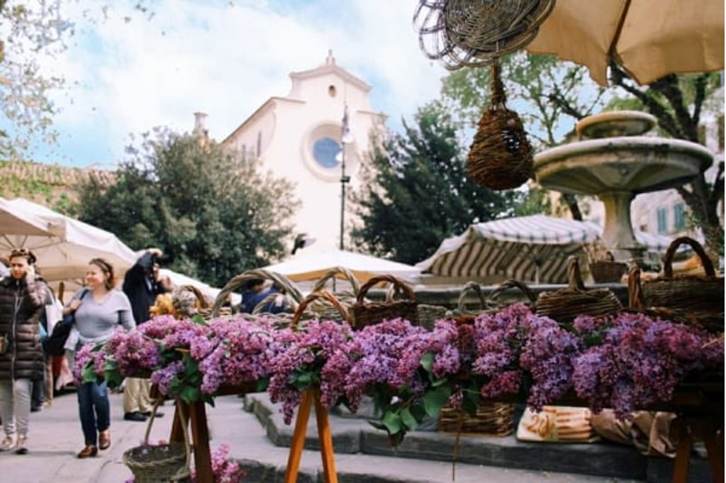 Flower and plant stalls at the Fierucola in a Florentine square, with a church facade in the background
