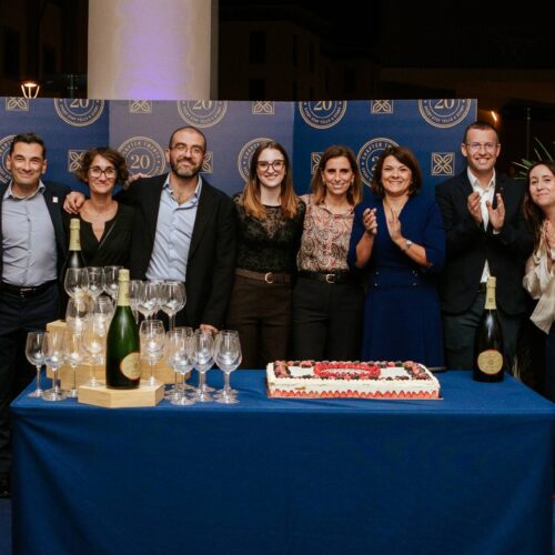 Lo staff dell'Hilton Garden Inn Florence Novoli davanti al pannello dei vent'anni, con torta, calici e spumante