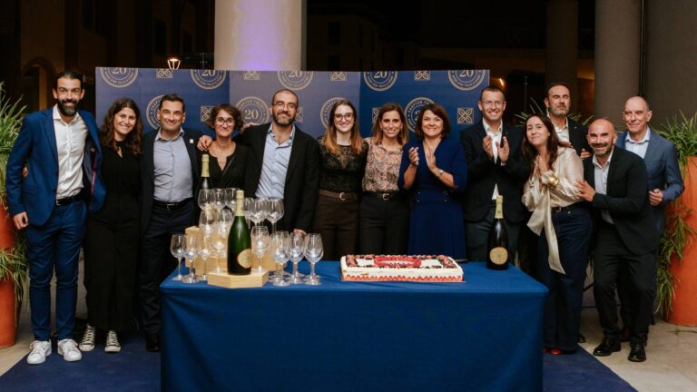 Lo staff dell'Hilton Garden Inn Florence Novoli davanti al pannello dei vent'anni, con torta, calici e spumante