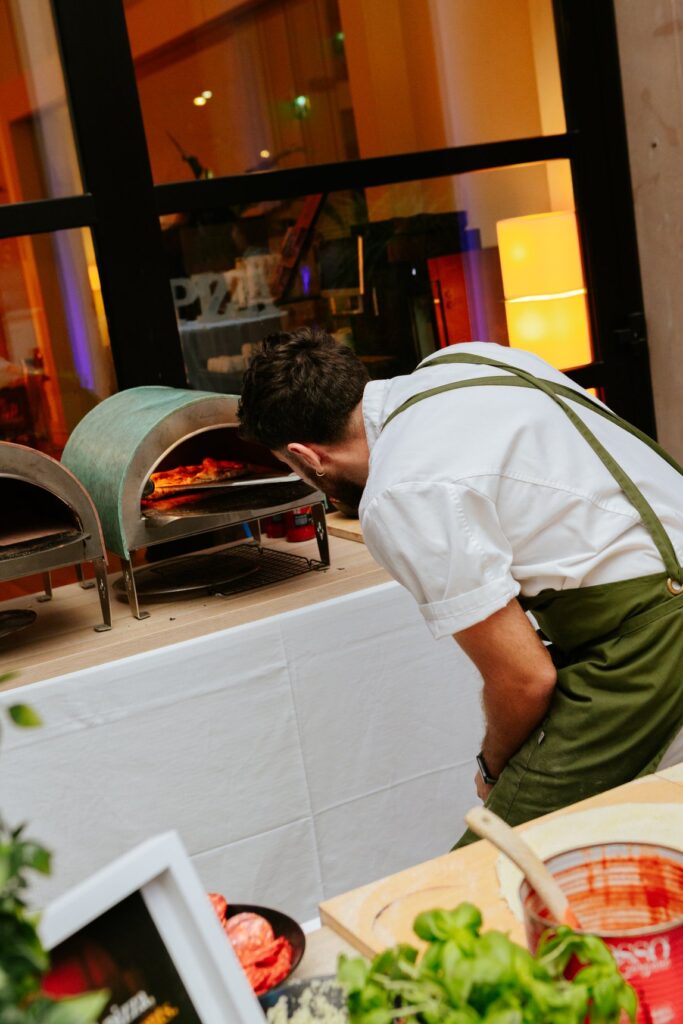 Un pizzaiolo controlla la pizza nel forno a una delle postazioni gastronomiche della festa per i vent'anni dell'hotel