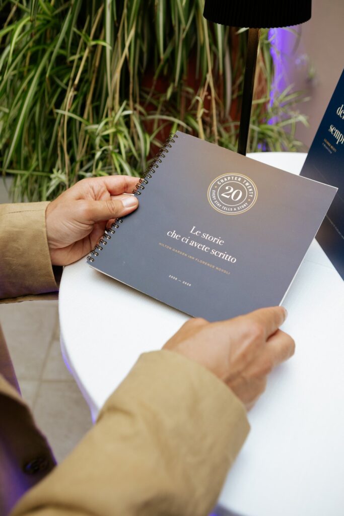 Due mani tengono il libretto «Le storie che ci avete scritto» con le testimonianze per i vent'anni dell'hotel