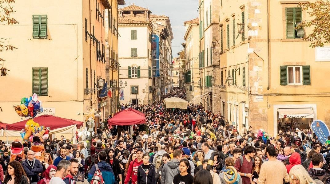 Una via del centro di Lucca gremita di pubblico, con i gazebo rossi e i palloncini colorati del festival