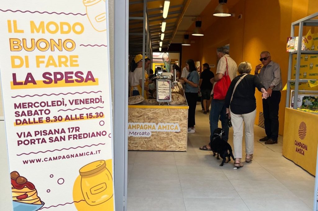 Entrance to the Campagna Amica market at Porta San Frediano, with the opening-hours sign and the stalls inside