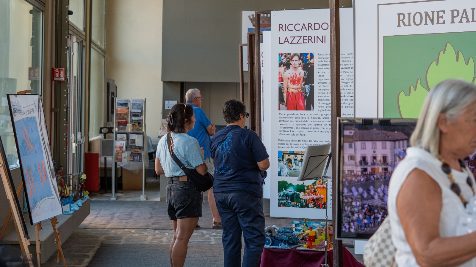 Visitors in front of the panels devoted to the Personaggi of the four rioni at the Loggiato del Pellegrino in Impruneta