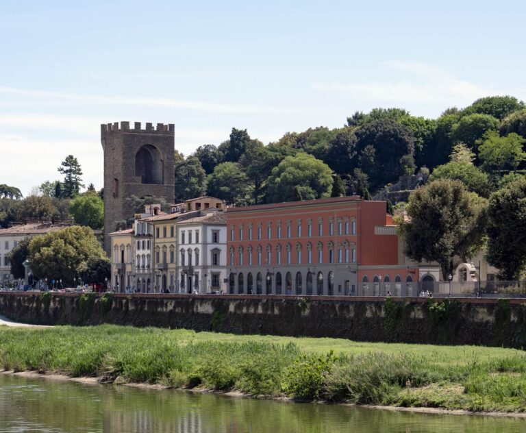 Palazzo San Giorgio visto dall'altra sponda dell'Arno: la facciata rossa sul lungarno, a sinistra una torre medievale