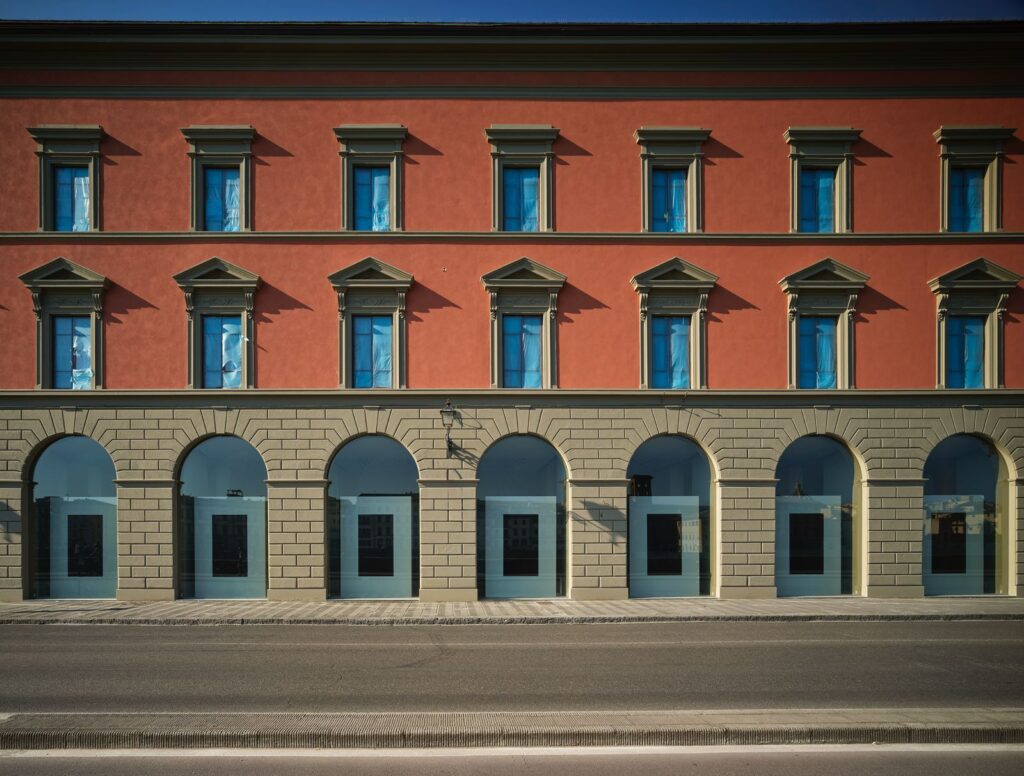 La facciata restaurata di Palazzo San Giorgio: intonaco rosso, finestre con timpano e arcate al piano terra