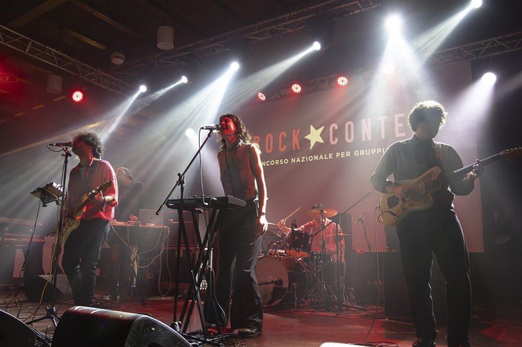 The Rock Contest stage: a band plays under beams of white light, with the festival banner in the background