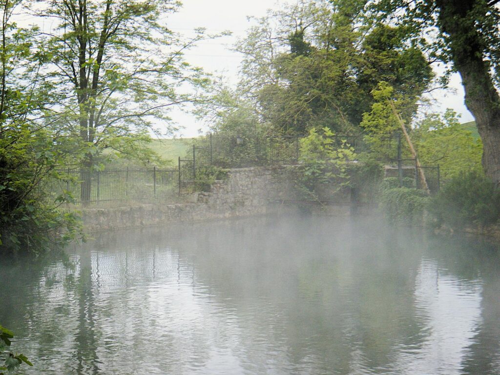 La Vasca grande di San Casciano dei Bagni con il vapore dell'acqua calda che sale tra gli alberi