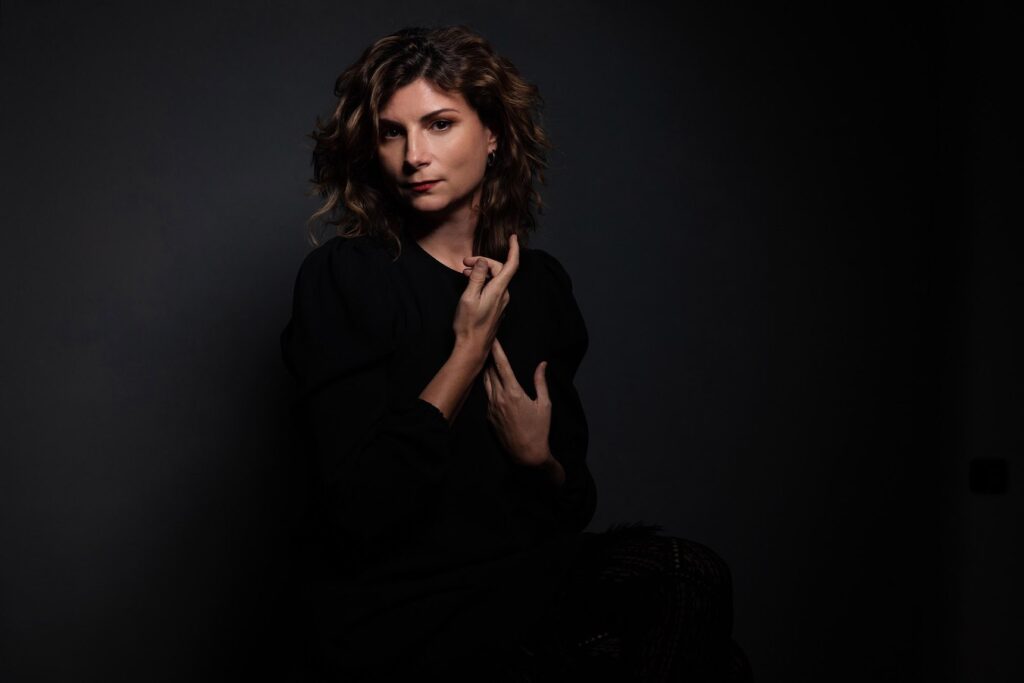 La pianista Tania Giannouli, vestita di nero, con le mani alzate davanti a un fondo scuro