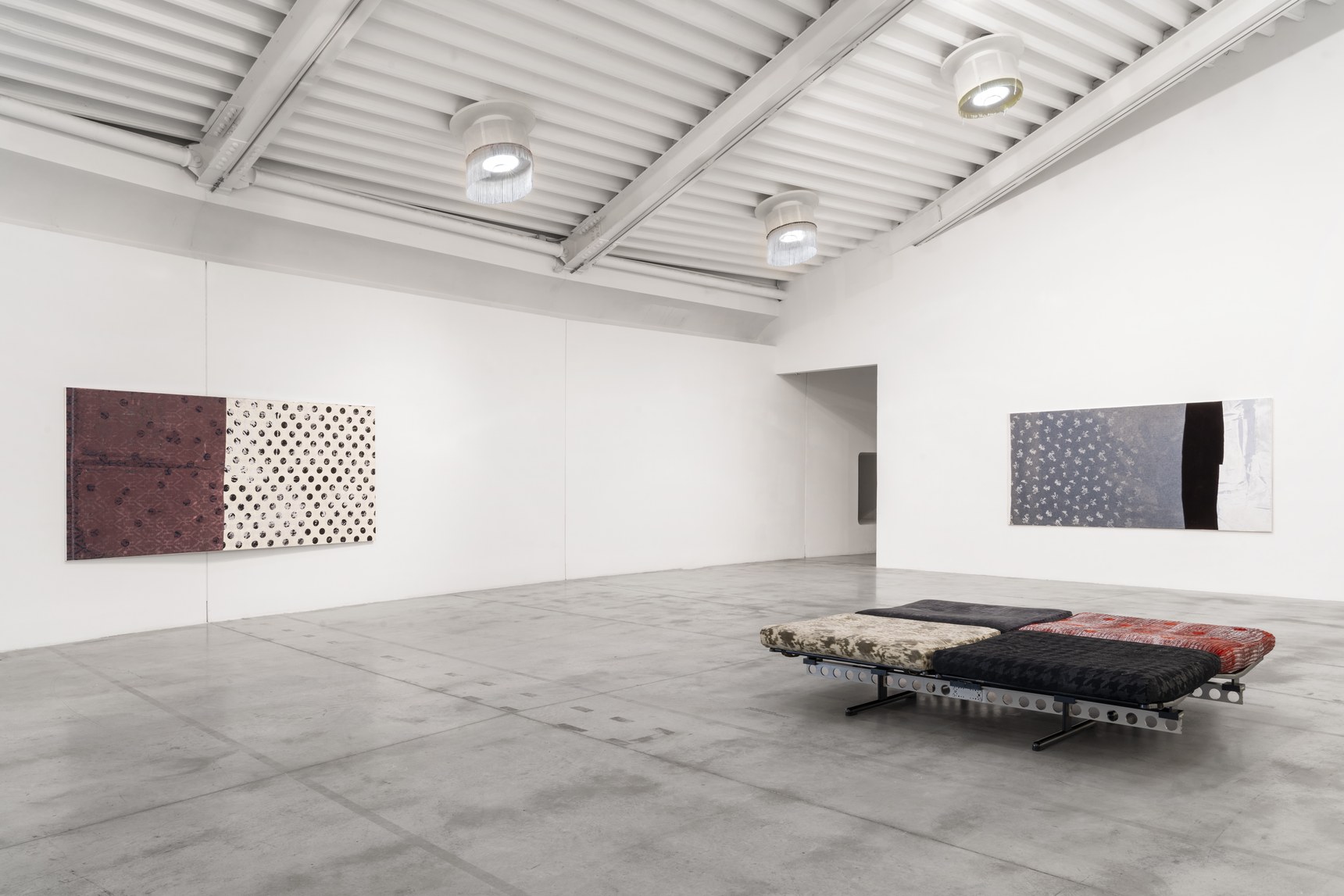Two of the museum’s historic sofas covered in printed fabric in front of canvases hanging on white walls