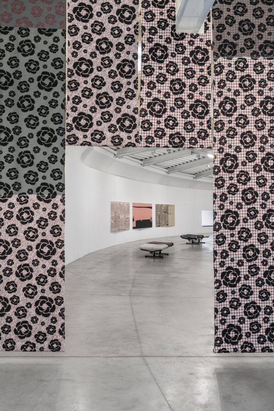 Pillars wrapped in a large black floral fabric frame the exhibition room at Centro Pecci
