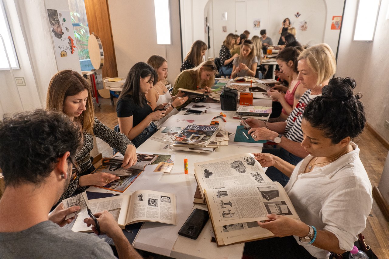 Partecipanti a un laboratorio di collage ritagliano pagine di riviste lungo un tavolo condiviso