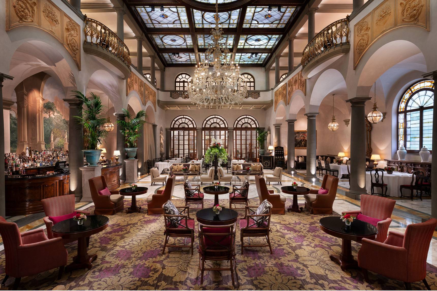 La sala del Winter Garden del St. Regis Florence con la grande vetrata a lucernario, il lampadario e le poltrone rosse