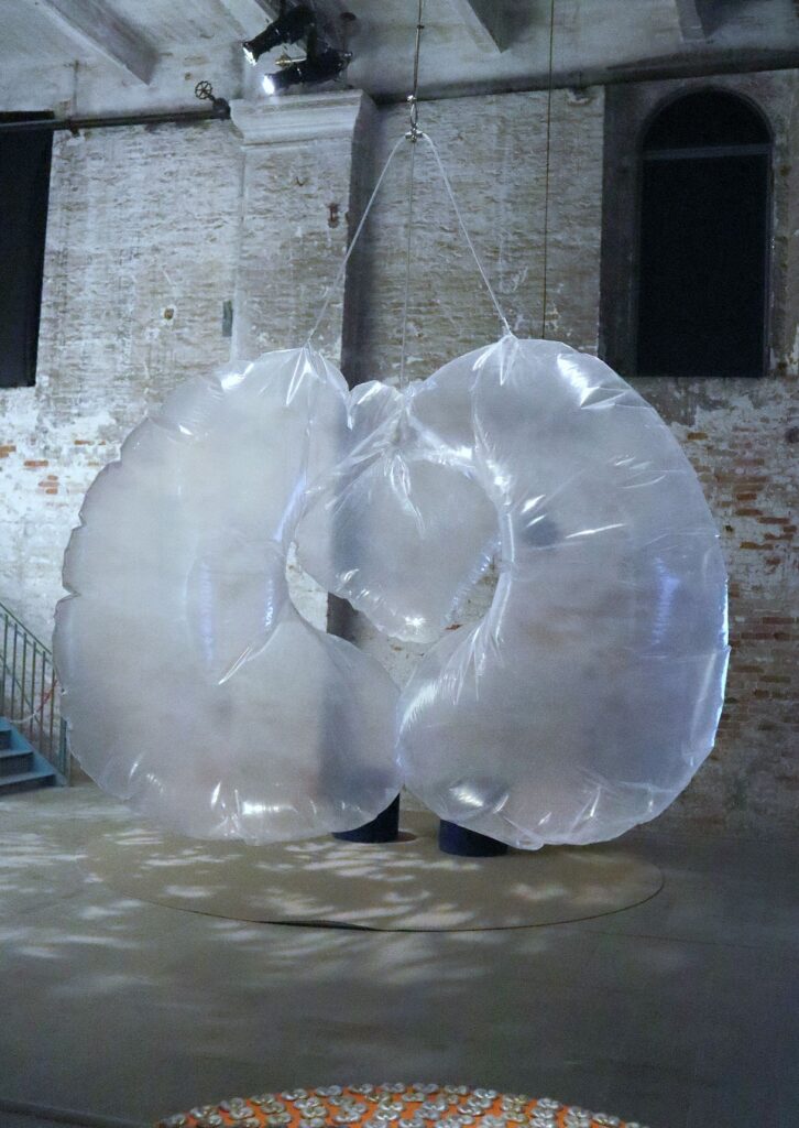 Una scultura gonfiabile trasparente sospesa a dei fili in una sala dai muri di mattoni, alla Biennale Arte 2026
