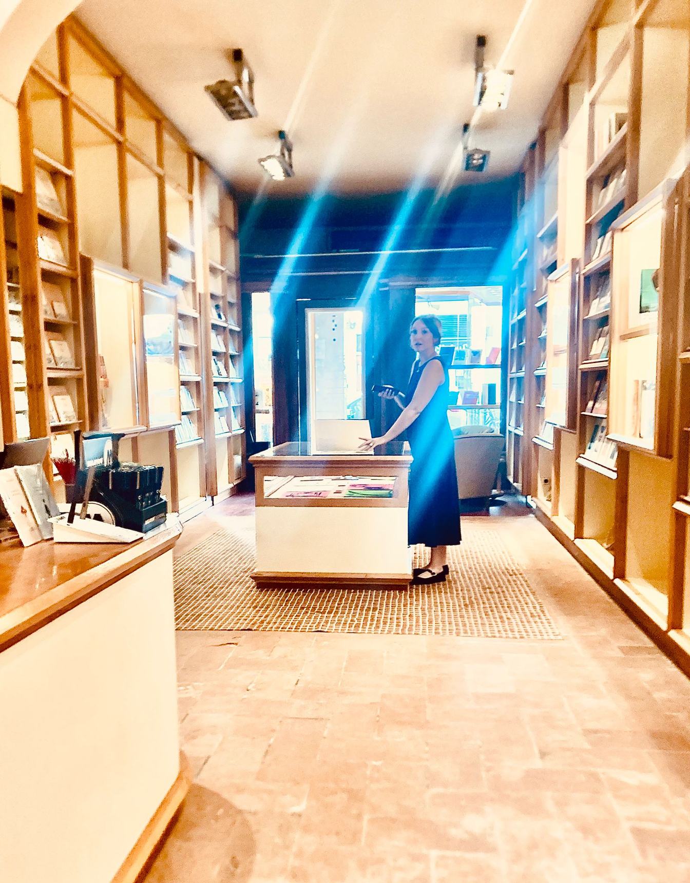 La lunga sala di Brac & Co. a Firenze, con scaffali di libri in legno chiaro e un bancone al centro