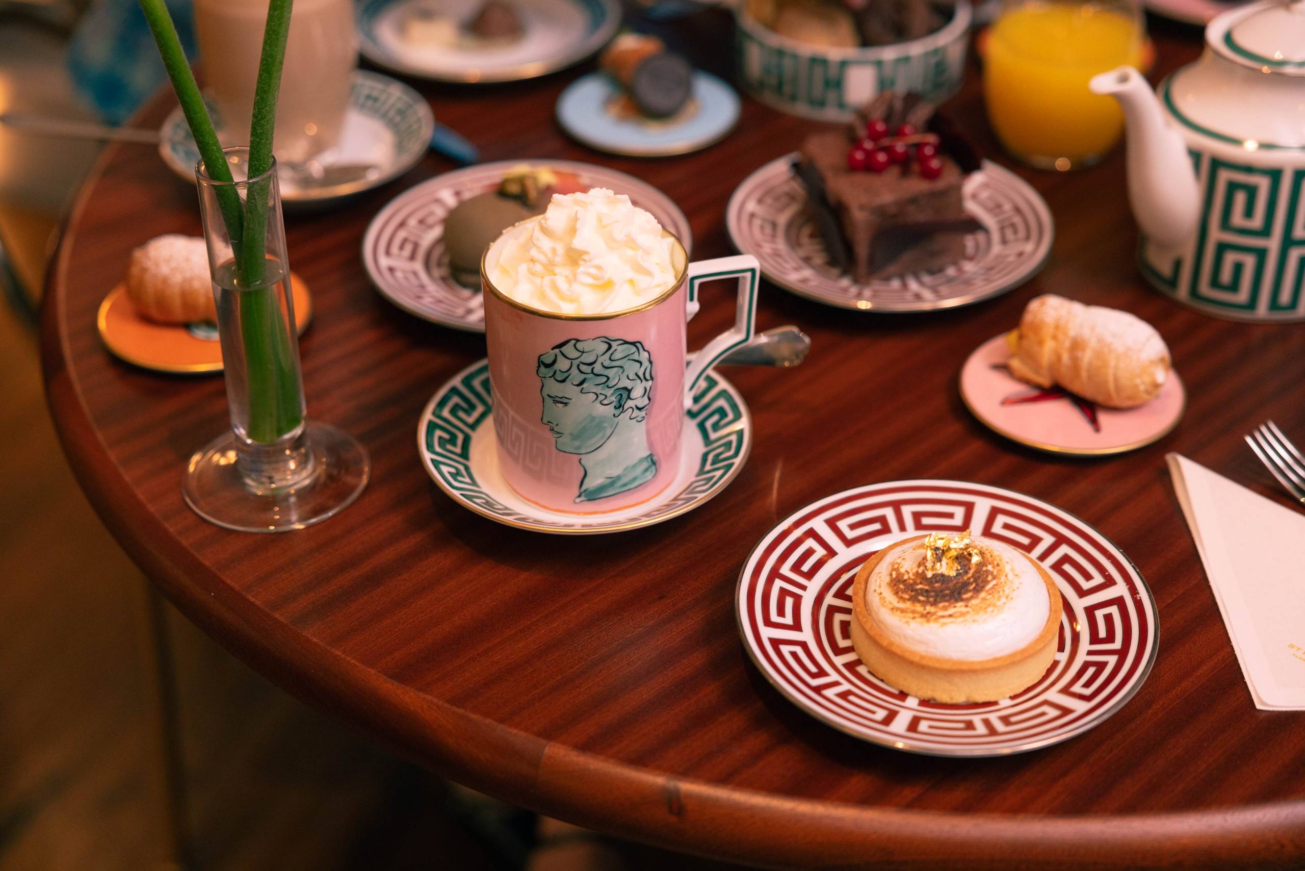Tavolo del Café Ginori apparecchiato per il brunch con porcellane Ginori, cappuccino con panna, pasticcini e succo d'arancia