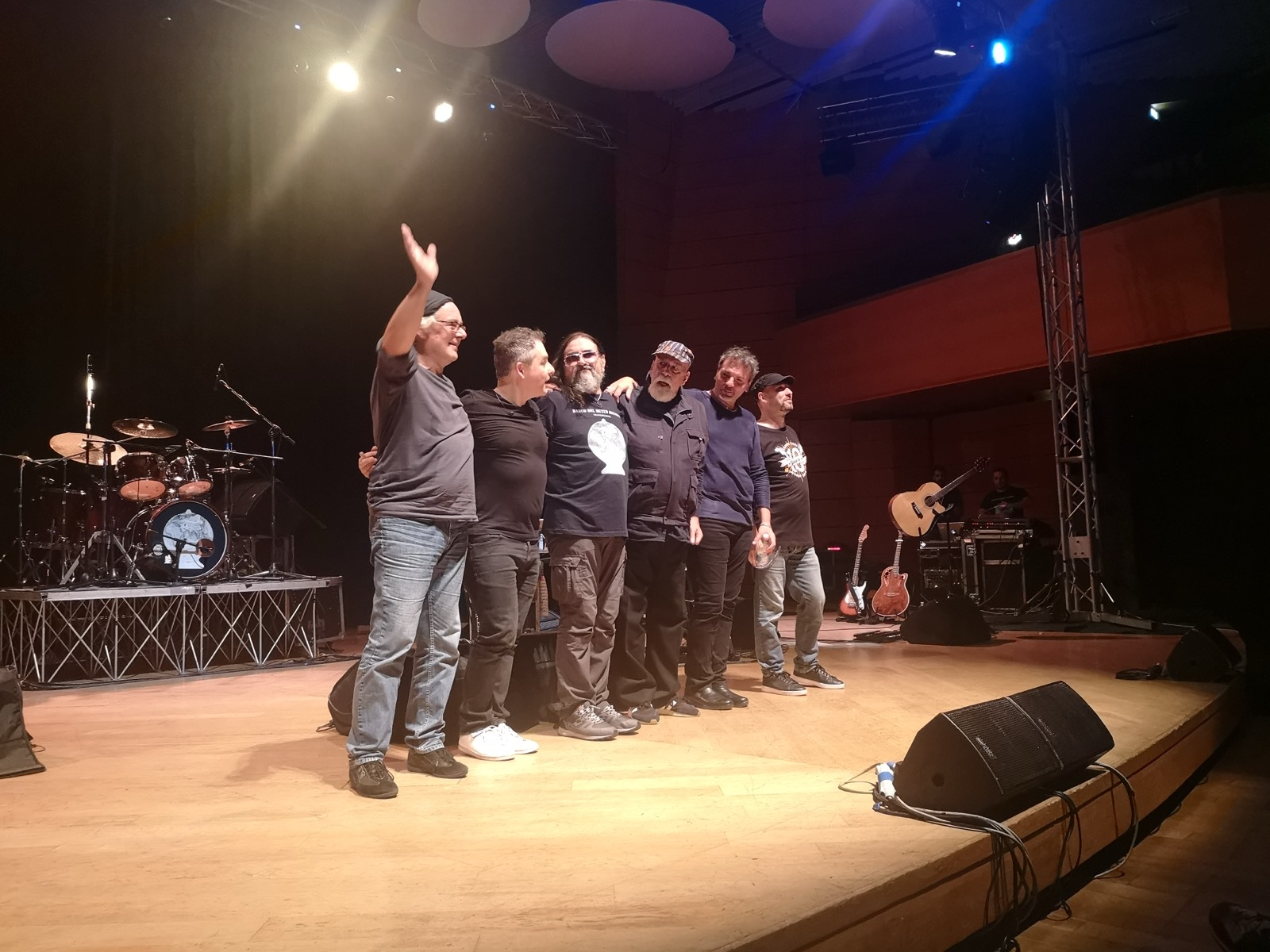 I sei musicisti del Banco del Mutuo Soccorso salutano il pubblico abbracciati sul palco, con la batteria alle spalle