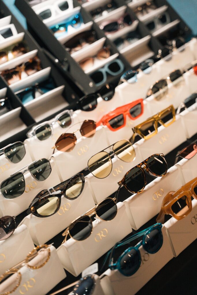 Occhiali da sole vintage con montature di colori diversi disposti in file su un espositore di East Market