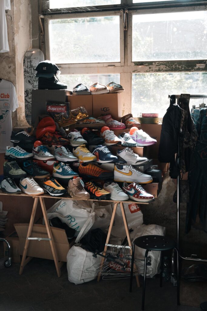 Sneakers usate impilate su scaffali sotto una finestra e giacche appese a uno stand di East Market a Firenze