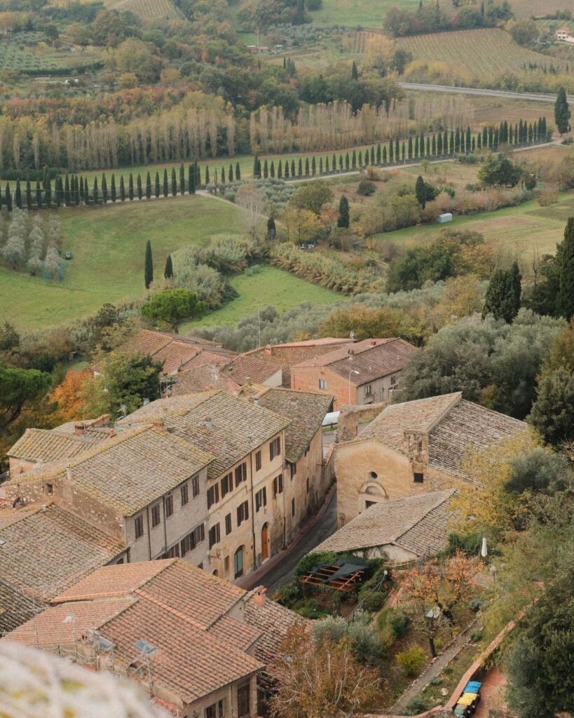 La campagna toscana vista dall'alto in autunno: tetti in coppi, uliveti, vigne e filari di cipressi