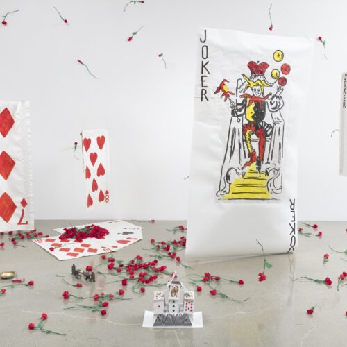 Installazione di Karen Kilimnik: carte da gioco giganti, fra cui un Joker, e garofani rossi sparsi sul pavimento