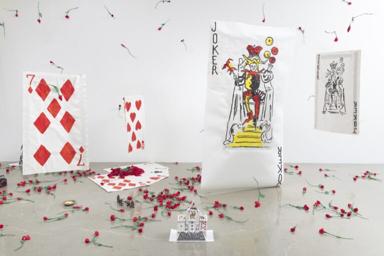 Installazione di Karen Kilimnik: carte da gioco giganti, fra cui un Joker, e garofani rossi sparsi sul pavimento