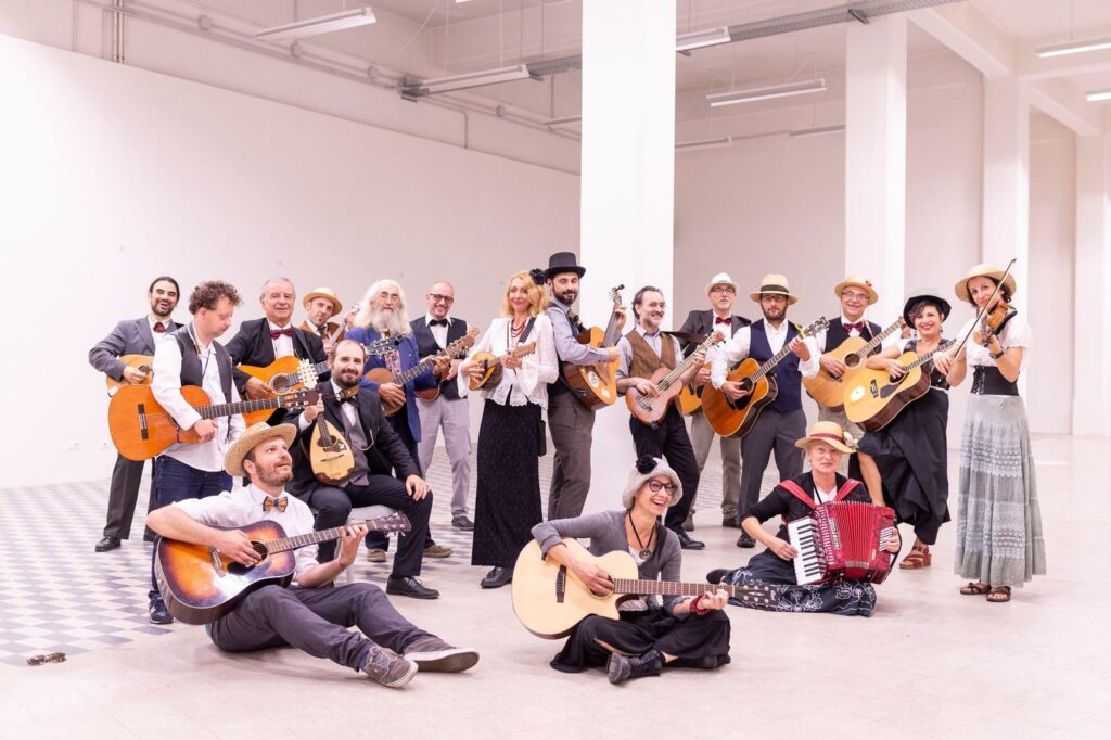 I musicisti de La Nuova Pippolese con chitarre, mandolini, violino e fisarmonica in posa in una grande sala bianca