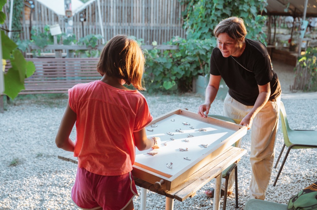 Una bambina e un'adulta giocano insieme a un grande gioco da tavolo in legno, all'aperto, nel giardino di Lumen