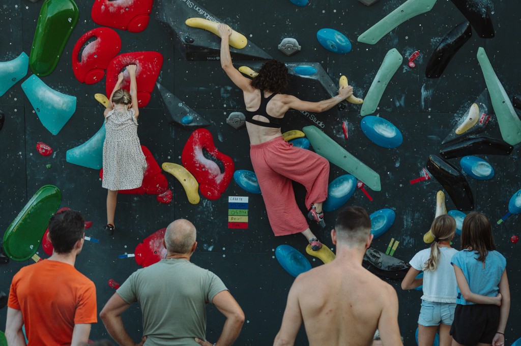 La parete d'arrampicata di Lumen con prese colorate: due persone salgono e altre le guardano dal basso