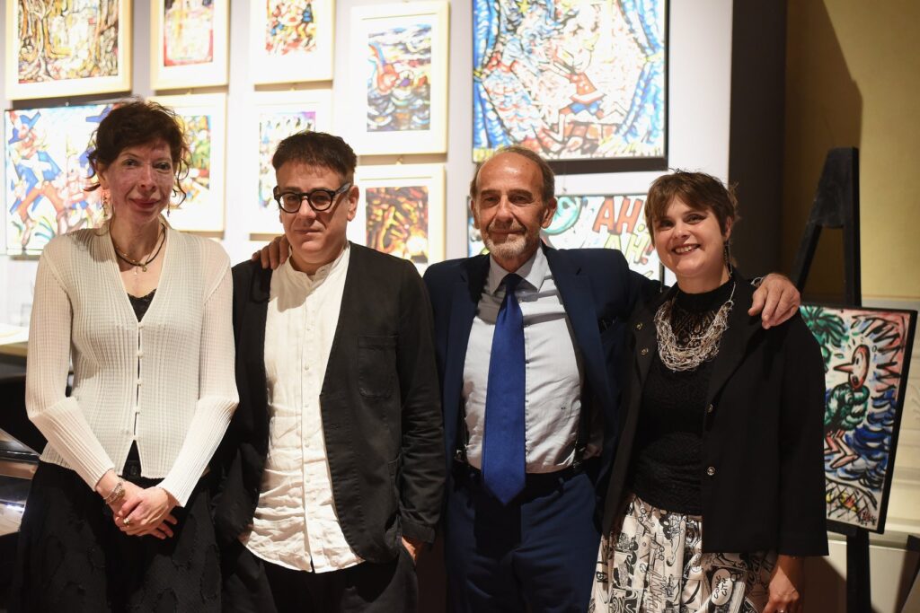 Benedetta Gallerini, Michele Rossi, Riccardo Nencini ed Elisa Martini in posa davanti a una parete di opere su Pinocchio