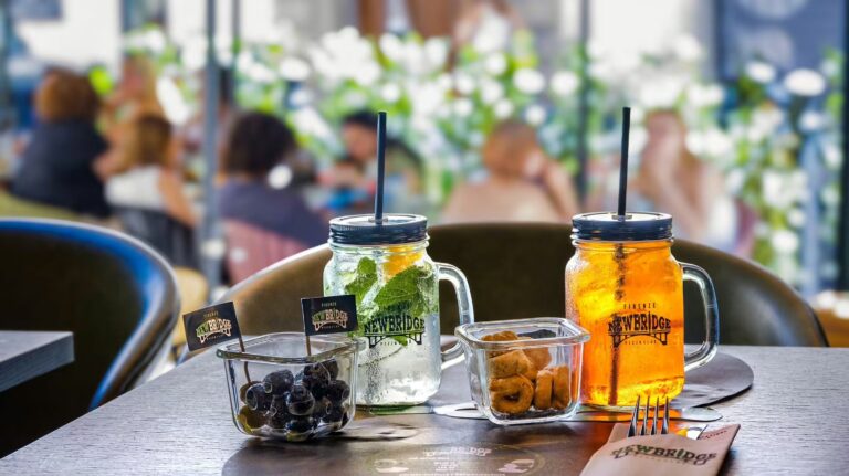 Due drink nei boccali di New Bridge con olive e stuzzichini su un tavolo all’aperto del New Bridge Pizza Club a Firenze