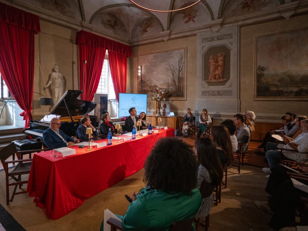 Il pubblico in una sala affrescata con tende rosse alla presentazione della stagione della New Generation Foundation