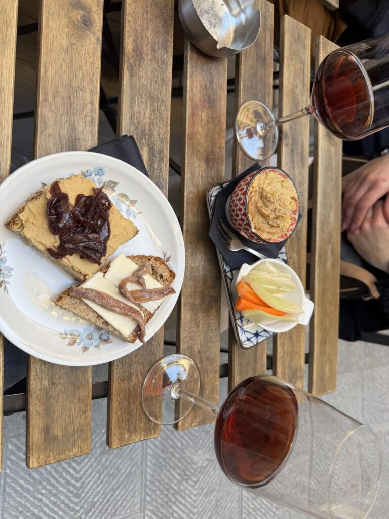 Due calici di vino rosso e crostini con acciughe e cipolla su un tavolo di legno della Vineria Sonora a Firenze