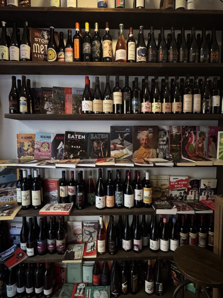 Scaffali di bottiglie di vino e libri di cucina alla Vineria Sonora, l’enoteca di via degli Alfani a Firenze
